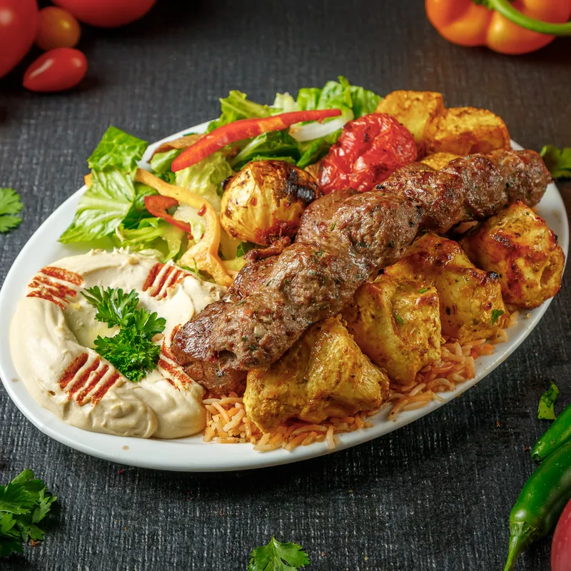 Beef kabab and shish tawouk on a plate with hummus and salad