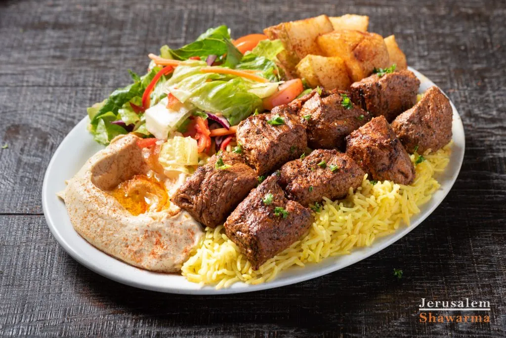 Beef kebab plate with rice, hummus and salad
